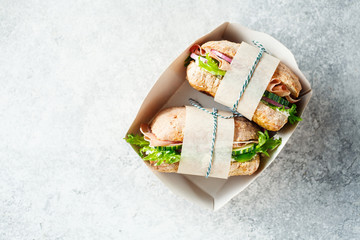 Two fresh sandwiches with ham, cucumbers, lettuce and onions