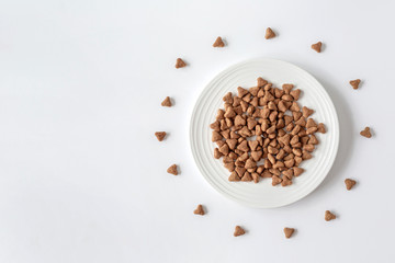 Domestic cat food. Minimalism top view flat lay plate with white dry food. Pet care.