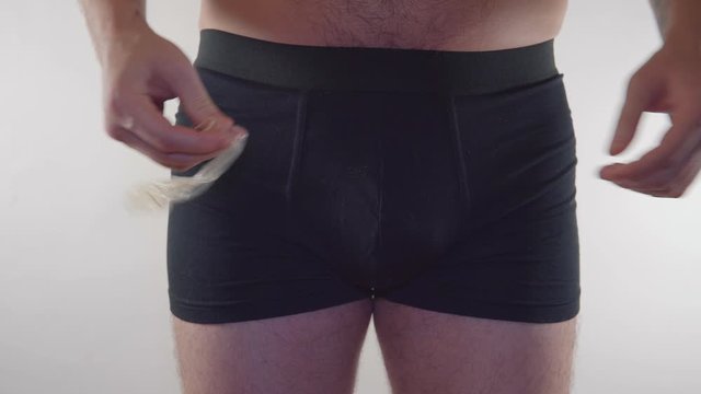 Close-up of a man in underwear holding a condom on an white background. Man in underwear holding a condom and a contraceptive. Contraception - man in underwear