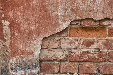 the old plaster on the brick wall is falling off