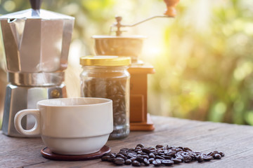 A cup of hot espresso coffee mugs and roasted coffee beans with moka pot placed on wooden floor background,coffee morning,selective focus