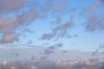 low-floating Cumulus clouds at dawn against a blue sky