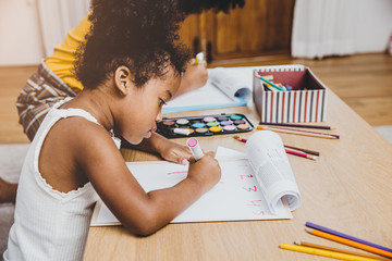 American Black preschool daughter kids doing homework learning education with her sister living together at home. - obrazy, fototapety, plakaty