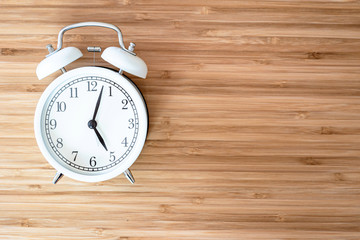 White retro alarm clock on brown wood desk with copy space