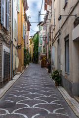 Fototapeta na wymiar Empty uphill street with cobblestones in Antibes, France 
