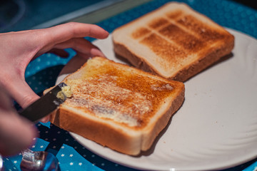hands spreading butter on toast