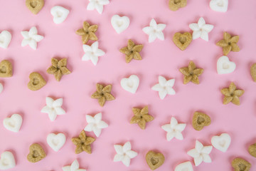 Top view on sugar in the shape of heart and flower on a pink background