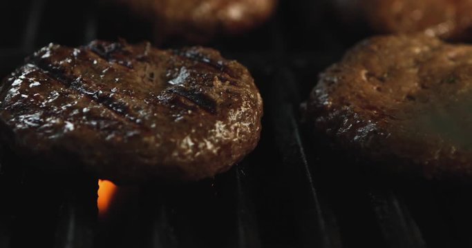 4K: Hamburgers Being Flipped On A Fiery Grill