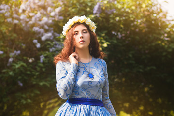 Attractive woman in a blue magnificent dress walks in the park against the background of blooming...