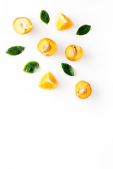 Peach slices and leaves background on white table top-down frame copy space