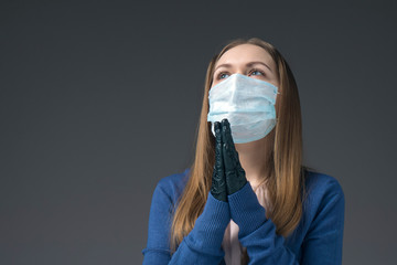 A girl in a mask and gloves prays. Virus protection.