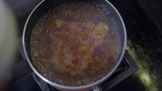 Close up water boiling on pan. Man boiling the water with chopped tomatoes. Cooking soup. Cooking tomato egg soup.