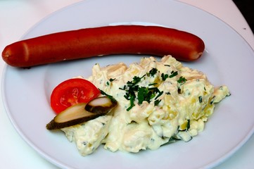 German sausage with potato salad, tomato and pickled cucumber in Cologne, Germany
