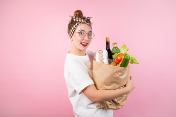 Beautiful girl holding a bag of food standing on a pink background
