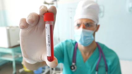 Scientist holding test tube with blood sample to coronavirus. Arm of laboratory worker with...