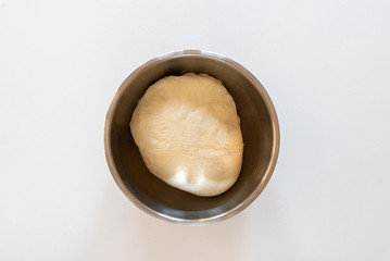 Handmade dough for bread in a metal bowl on white marble background, homemade cooking.