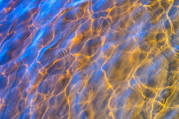 Glare of the sun and waves at the bottom of the river