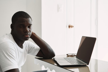 A man of African appearance at home in front of a laptop relaxing