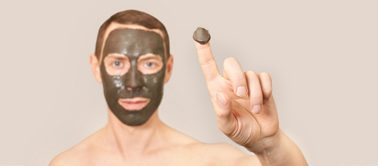 Black Clay Mask on Guy Face. Cosmetology man portrait with mud healthy scrub. Coal nature eco masque. Dermatology mud. Home skin care routine. Skincare male treatment. Applying pure ecology product