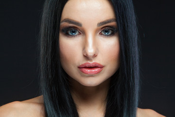 Closeup of beautiful woman face with beauty makeup and long brunette hair looking at camera...