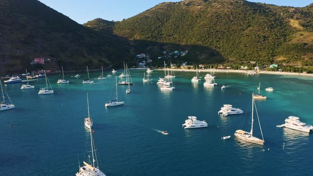 Jost Van Dyke (British Virgin Islands) drone aerial tilt reveal harbor shot over anchored sailboats to shore