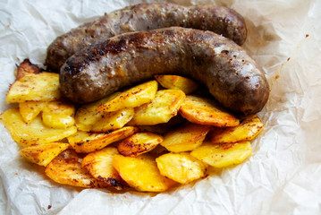 On parchment paper, a traditional German dish, potatoes and fried sausages