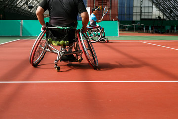 Disabled mature man on a wheelchair playing tennis on an indoor tennis court. Copy space