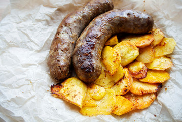 On parchment paper, a traditional German dish, potatoes and fried sausages