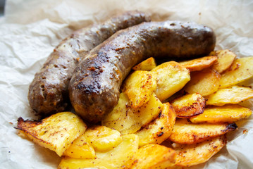 On parchment paper, a traditional German dish, potatoes and fried sausages