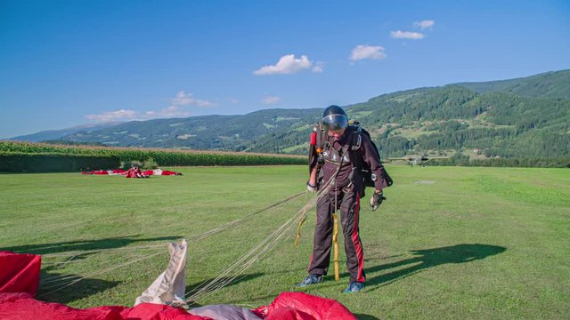 Skydiver arranges his parachute on the ground after his jump