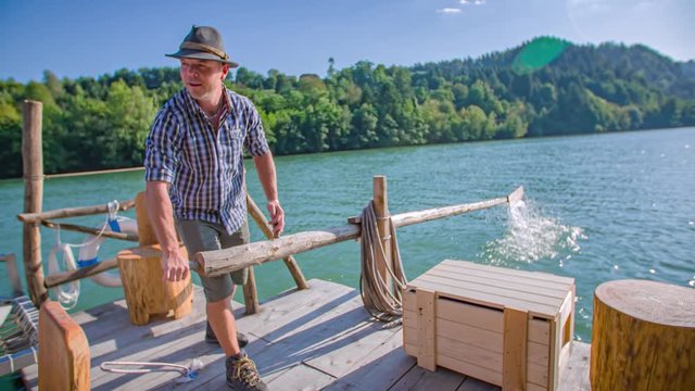 Timber raftsman on the Drava river stream using oars to steer a log-raft ride