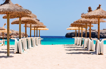 Straw parasols and beds on the sandy beach