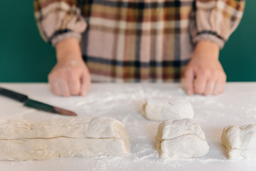 Obraz na płótnie Canvas Woman cuts pieces of dough to prepare her handmade bread, homemade cooking.
