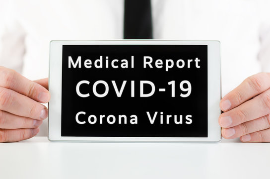 Businessman holding a smart tablet with sign Medical Report Covid-19 Corona Virus