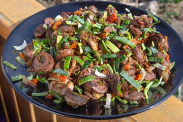 fried chicken hearts with green onions on a large black plate