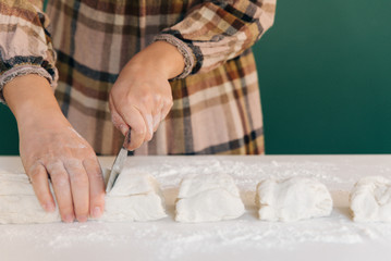 Woman cuts pieces of dough to prepare her handmade bread, homemade cooking.