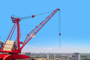 Fototapeta na wymiar The big red crane is working on a tall building.