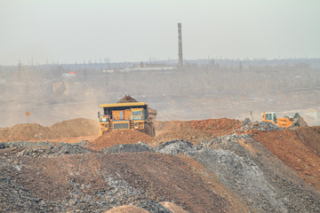A large mining truck dumps waste rock to a dump