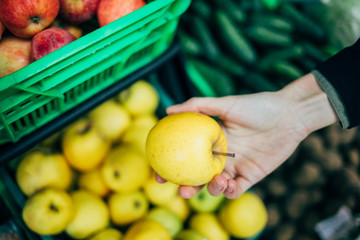 Female hand picking apple from shelf