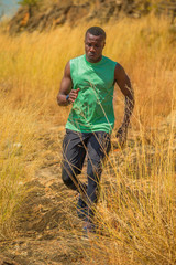 Naklejka na ściany i meble african man Trail running in Meadow on mountain outdoor. sport adventure . black man runner jogging on country path or cross-country in summer . healthy lifestyle