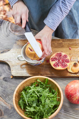 woman's hands with kitchen knife in hand dressing salad with pomegranate seeds