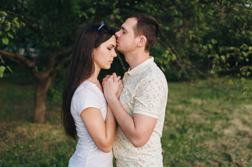 Lovers, beautiful, stylish guy and a girl in tracksuits hug in the forest, outdoors in a green garden. Love story newlyweds. Photography, concept.