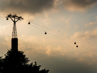 Cable cars between Singapore and Sentosa island silhouetted against dark ominous clouds