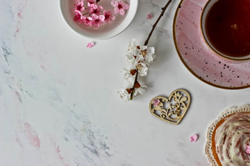 Cinnamon roll, tea and flowering sprigs on a white background