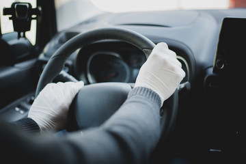 A man driving a car wearing hand gloves as a part of infection protection