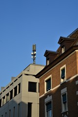 Fototapeta na wymiar Mobile antenna on a house roof with a beautiful blue sky in the city of Zurich Switzerland