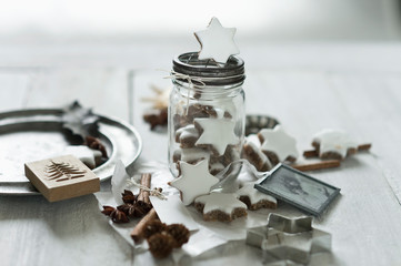 Star shaped cookies, cinnamon sticks, old photograph, pine cones, cookie cutter, star anise, glass jar and Christmas decorations