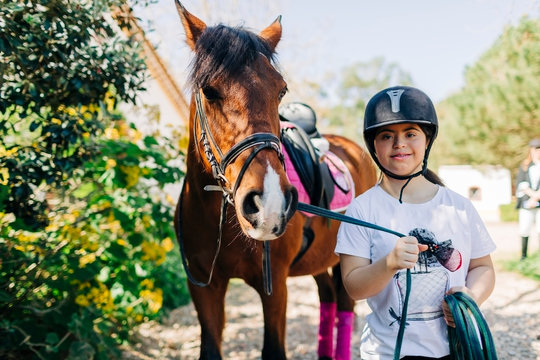 Teenager with down syndrome taking care of horse and preparing horse to ride