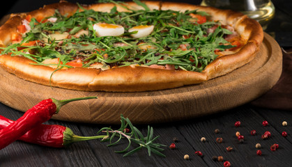 pizza with arugula on a black wooden background