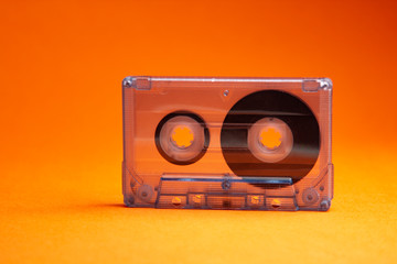 Transparent audio cassette tape orange background. Front, view.